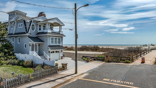 view of front of house featuring a fenced front yard, a balcony, a garage, a shingled roof, and a chimney