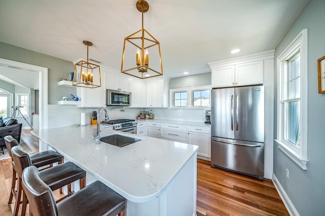 kitchen featuring a peninsula, white cabinetry, appliances with stainless steel finishes, and a sink