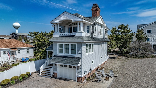 view of front of property with decorative driveway, a chimney, stairway, fence, and a garage