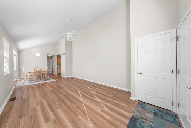 interior space featuring light wood-type flooring, visible vents, high vaulted ceiling, baseboards, and ceiling fan