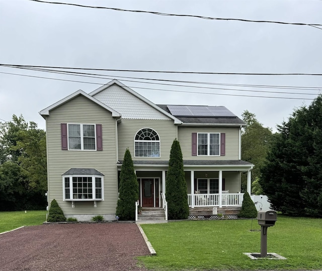 view of front of house with solar panels, a porch, and a front lawn