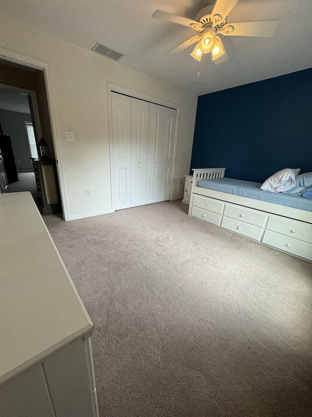 unfurnished bedroom featuring light carpet, a closet, and ceiling fan