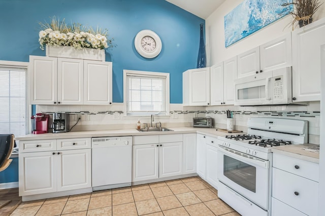 kitchen featuring white cabinetry, sink, white appliances, decorative backsplash, and light tile patterned floors