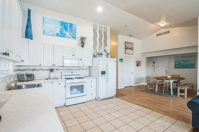 kitchen with tasteful backsplash, white cabinetry, sink, and white appliances