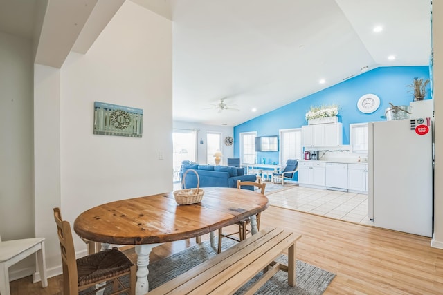 dining area with ceiling fan, vaulted ceiling, and light hardwood / wood-style flooring