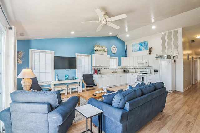 living room featuring ceiling fan, sink, lofted ceiling, and light wood-type flooring