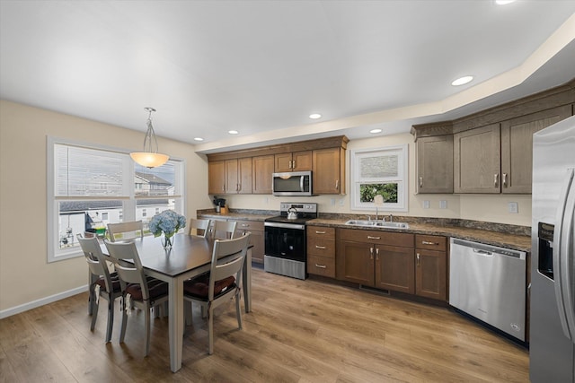 kitchen featuring sink, hardwood / wood-style floors, decorative light fixtures, and appliances with stainless steel finishes