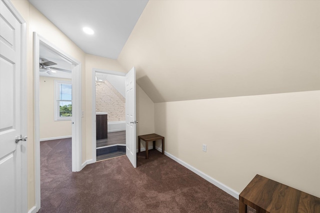 additional living space featuring dark colored carpet, vaulted ceiling, and ceiling fan