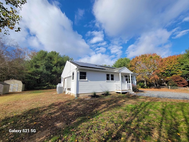 view of front of property with a storage shed, a front lawn, and solar panels