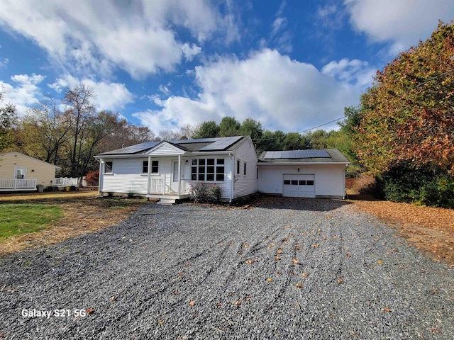 single story home featuring covered porch, a garage, and solar panels