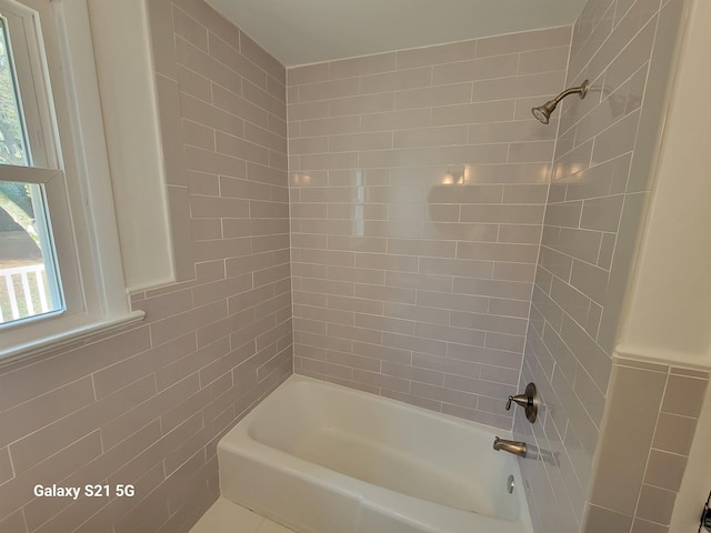 bathroom featuring tiled shower / bath combo and tile walls