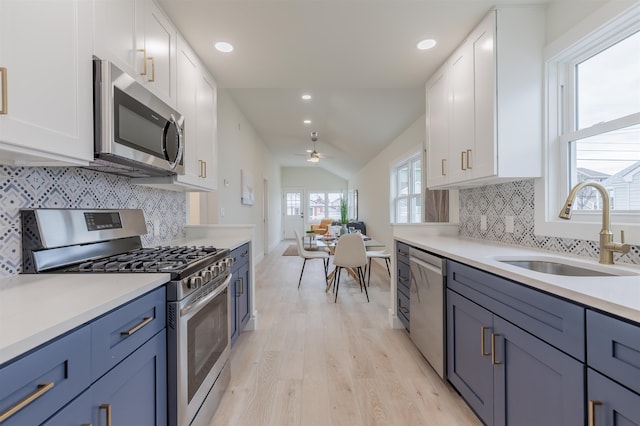 kitchen with light countertops, light wood-style flooring, appliances with stainless steel finishes, white cabinetry, and a sink