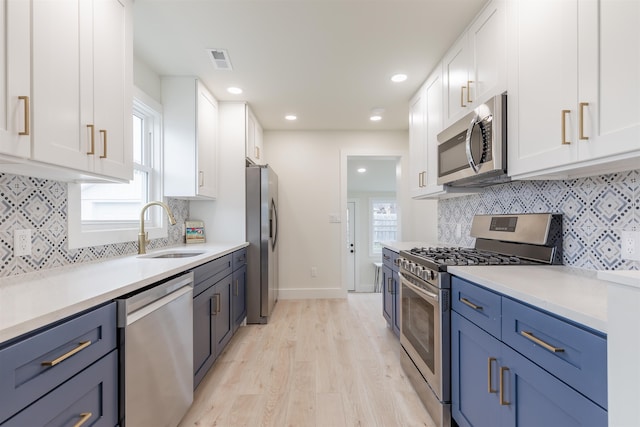 kitchen featuring visible vents, white cabinets, appliances with stainless steel finishes, light wood-type flooring, and a sink