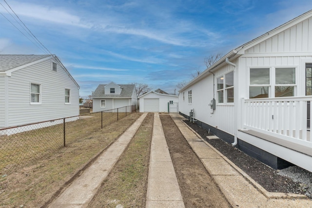 view of home's exterior featuring an outbuilding, board and batten siding, fence, a garage, and driveway