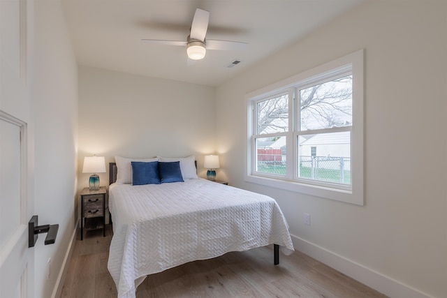 bedroom with light wood finished floors, visible vents, baseboards, and ceiling fan