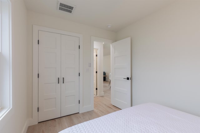 bedroom with baseboards, a closet, visible vents, and light wood-style floors