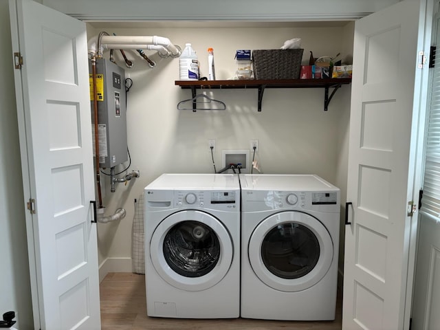 clothes washing area with water heater, laundry area, separate washer and dryer, and wood finished floors