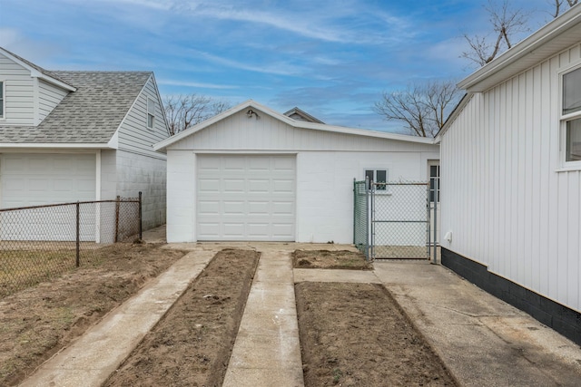 garage featuring driveway, fence, and a gate