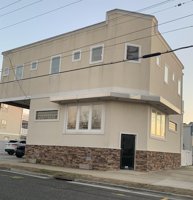 view of side of home featuring stone siding and stucco siding