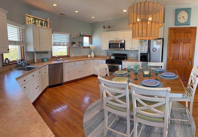 kitchen with white cabinets, appliances with stainless steel finishes, a sink, and light countertops