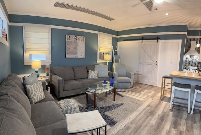 living room with recessed lighting, a barn door, wood finished floors, and ornamental molding