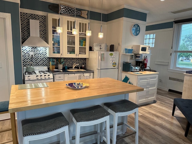 kitchen featuring wall chimney range hood, wood counters, white appliances, and radiator