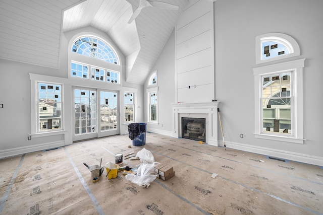 unfurnished living room with high vaulted ceiling, a fireplace, and baseboards