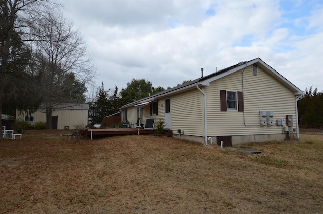 view of side of home with a lawn and a wooden deck