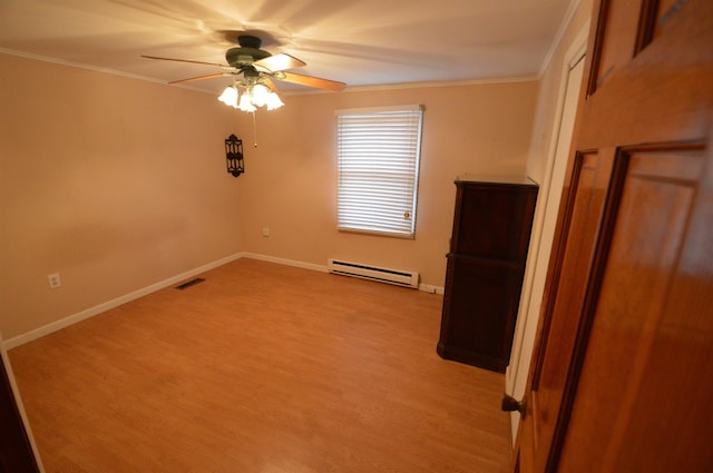 spare room with a baseboard heating unit, light wood-type flooring, ceiling fan, and crown molding