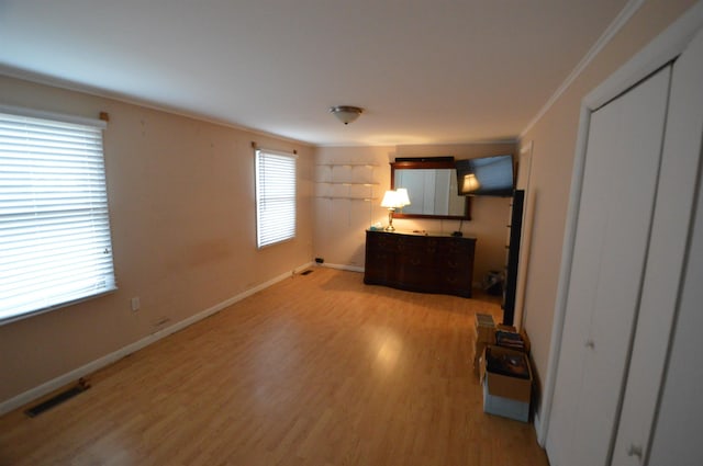 unfurnished bedroom with ornamental molding, light wood-type flooring, and a closet