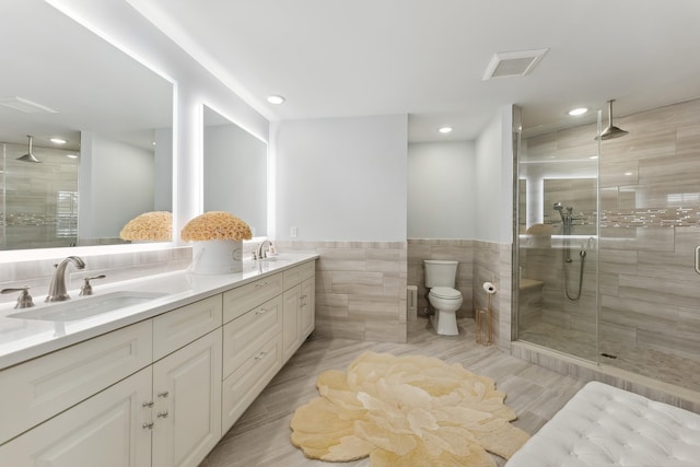 bathroom featuring double vanity, a stall shower, tile walls, and a sink