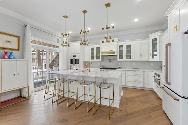 kitchen featuring light wood-type flooring, white appliances, and crown molding