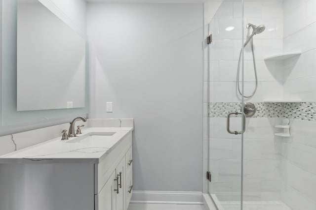 full bath featuring vanity, baseboards, and a stall shower