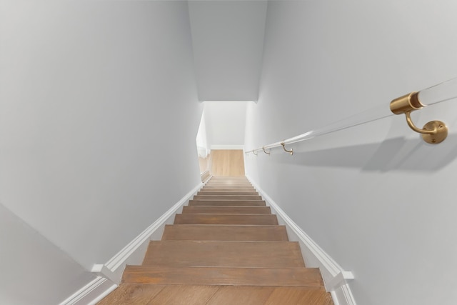 stairway with wood finished floors and baseboards