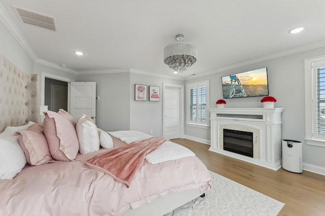 bedroom featuring a premium fireplace, visible vents, wood finished floors, and crown molding