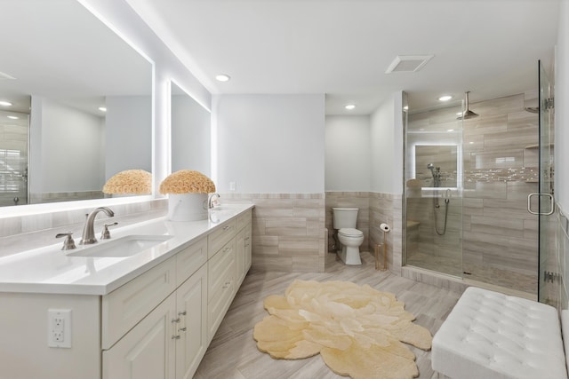 bathroom featuring visible vents, a stall shower, a sink, tile walls, and double vanity