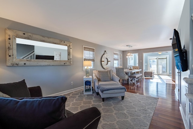 living area with a notable chandelier, baseboards, and wood finished floors