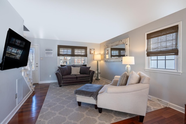 living area featuring wood-type flooring, visible vents, and baseboards