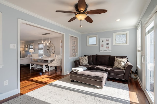 living area with baseboards, crown molding, and wood finished floors