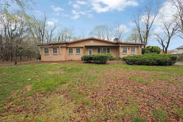 single story home with a chimney, a front yard, and stucco siding