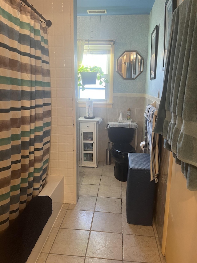 bathroom featuring toilet, tile patterned floors, tile walls, and a shower with curtain