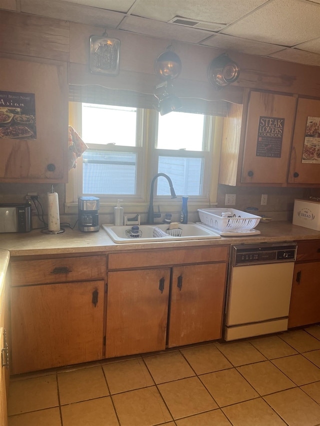 kitchen with white dishwasher, sink, and light tile patterned floors