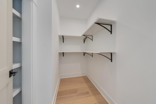 walk in closet with light hardwood / wood-style flooring