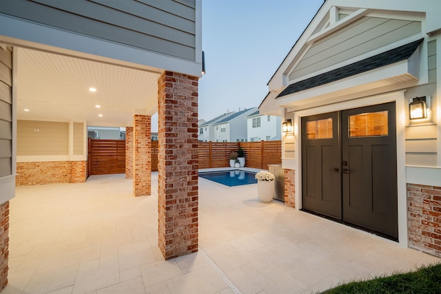 patio terrace at dusk featuring a fenced in pool