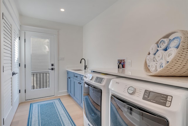 laundry area featuring cabinets, washing machine and clothes dryer, light hardwood / wood-style floors, and sink