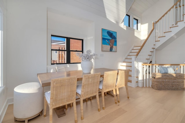 dining room with a wealth of natural light, light hardwood / wood-style floors, and a high ceiling