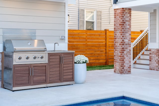 view of patio with exterior kitchen, a grill, and sink