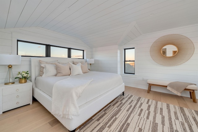 bedroom with vaulted ceiling, wooden walls, wood ceiling, and light wood-type flooring