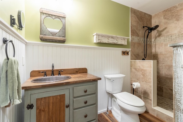 bathroom featuring toilet, a tile shower, hardwood / wood-style floors, and vanity