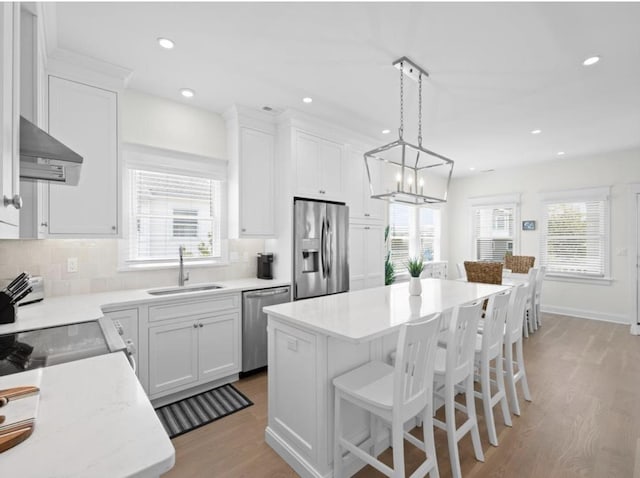 5765 Ocean Dr, Avalon, NJ 08202 - kitchen with appliances with stainless steel finishes, a sink, wall chimney exhaust hood, light countertops, and light wood finished floors